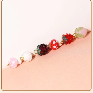 Detailed view of translucent fruit-shaped glass beads for DIY jewelry with gold metal loops