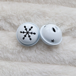 Close-up of white metal bells with cutout snowflake and star patterns on white faux fur