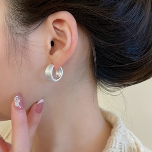 Close-up of minimalist matte silver hoop earring worn by a model in a lifestyle setting