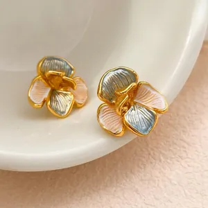 Elegant 3D flower stud earrings in pink and blue enamel on a white ceramic surface