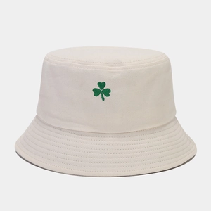 Détail de la broderie trèfle vert sur un chapeau bob en toile beige aux coutures nettes