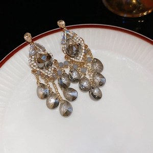 Detail of vintage gold earrings with grey teardrop crystals and beaded tassels on a tray