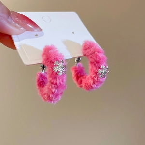 Close-up of pink flocked C-shaped hoop earrings with delicate metal snowflake charms