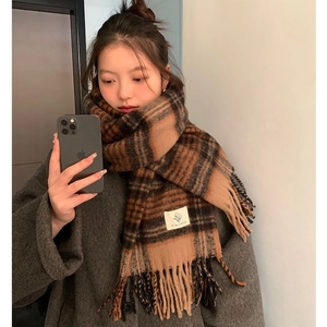 Close-up of brown plaid scarf featuring soft texture, fringe edges and white brand label