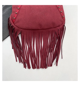 Detail of red suede tote bag with fringe, metal rivets and embossed sun pattern