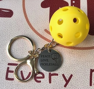 Detail of yellow pickleball keychain with Peace Love Pickleball engraving on round tag