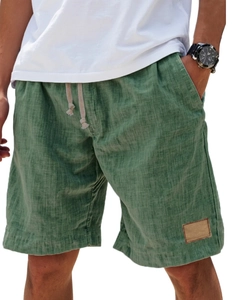 Detail of green linen men's leisure shorts featuring elastic drawstring waist and leather patch