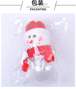 Close-up of a Christmas snowman candy jar in packaging with a red knitted scarf and hat