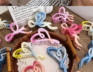 Detail shot of various gradient ribbon and heart claw clips on a wooden surface