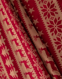 Close-up of red and beige Christmas reindeer jacquard fabric with snowflake texture