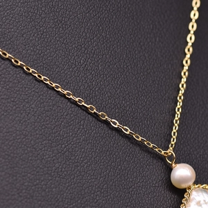 Elegant natural freshwater pearl necklace with a thin gold chain on black leather background