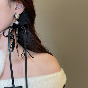Détail de boucles d'oreilles nœud en velours avec perles et pompons sur mannequin