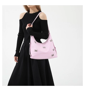 Pink nylon shoulder bag with silver butterfly charms shown on model in studio