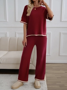 Detail of burgundy knitted set featuring beige stripe trim on short sleeves and trousers