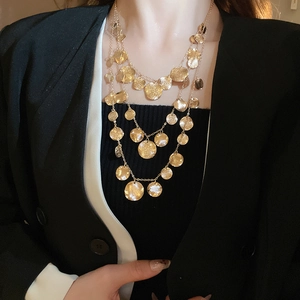 Detail of a three-layer gold hammered disc pendant necklace worn by a fashion model