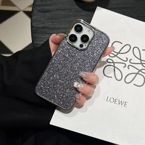 Detail of silver glitter phone case with metallic edges held by a hand near a bag