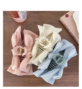 Flat lay of pink, cream, and blue oversized fabric bow hair claws on wood background