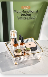 Detail of luxury square acrylic storage tray with gold edges and ball feet on marble surface