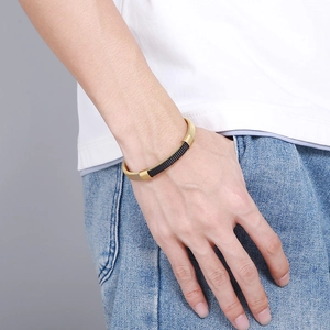 Close-up of men's woven stainless steel mesh bracelet in gold and black on wrist