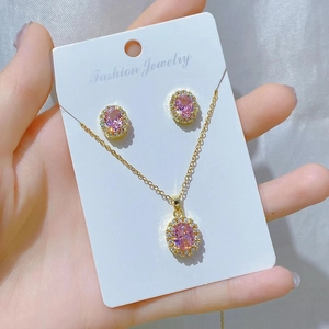 Close-up of gold necklace and earring set with pink oval stones on soft silk fabric
