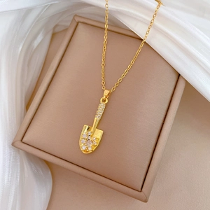 Elegant gold titanium shovel necklace with sparkling cubic zirconia on silk fabric