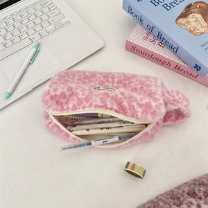 Detail of pink leopard plush pencil case with zipper and handle on a desk setup
