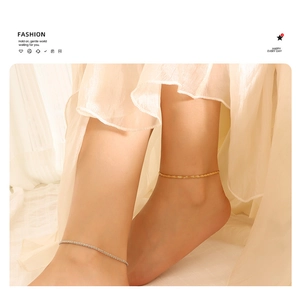 Close-up of gold and silver anklets with thin woven chain design on model's ankle