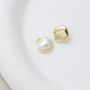 Macro shot of gold-plated heart charms and white pearl pendants for DIY jewelry making