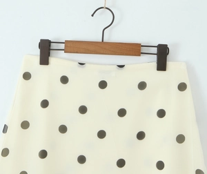 Detailed view of polka dot midi skirt in beige with black spots on a wooden hanger