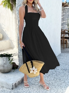Detail of a black halter midi dress with flowy fabric shown in a sunny outdoor setting