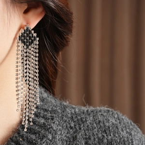 Close-up of vintage rhinestone tassel earrings with black geometric top on a model