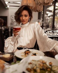 Élégante blouse en satin blanc à col montant et manches bouffantes dans un cadre chic
