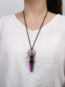 Detalle de colgante de bronce vintage con amatista y lunas sobre una camisa blanca