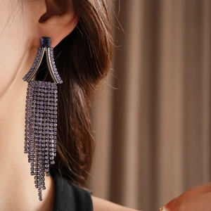 Close-up of long purple rhinestone tassel earrings featuring a square gemstone and silver frame