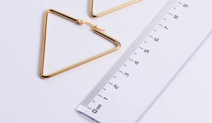 Detailed size comparison of 5cm triangle gold titanium steel hoop earrings with a ruler