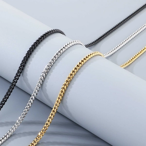 Close-up of Cuban chain links in black, silver, and gold finishes on a grey stand