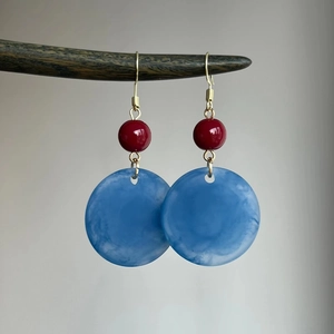 Gros plan de boucles d'oreilles rondes en acrylique mat bleu sur une branche naturelle