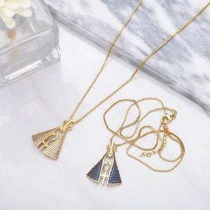Detailed macro view of gold religious pendant with white and blue stones and tiny cross