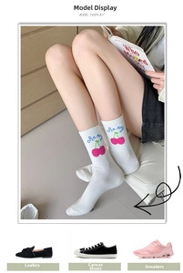 Close-up of white crew socks featuring cherry embroidery and cute blue lettering details