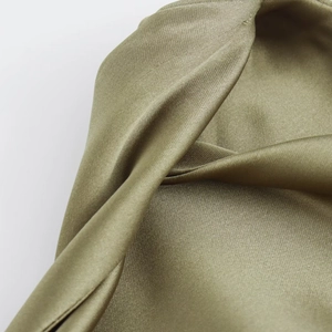 Macro view of olive green satin fabric showing smooth silk texture and elegant drape