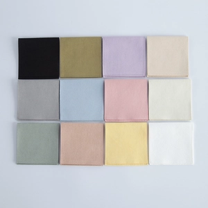 Flat lay of colorful velvet jewelry pouches in twelve different pastel and neutral shades