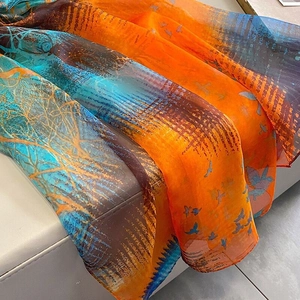 Detailed view of semi-transparent silk scarf with vibrant tree and bird print texture