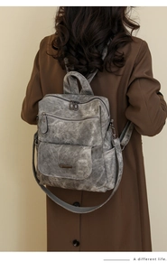 Detailansicht des grauen Vintage-Lederrucksacks mit mehreren Reißverschlussfächern
