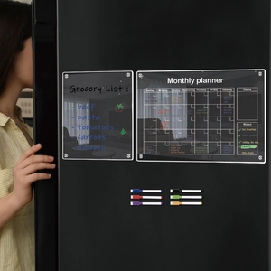 Detailed view of two magnetic acrylic calendars with colorful markers on a fridge door