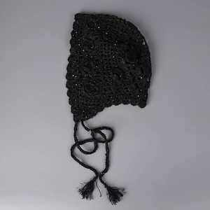 Detailed macro view of black sequined crochet knit texture with fringed ties on hat