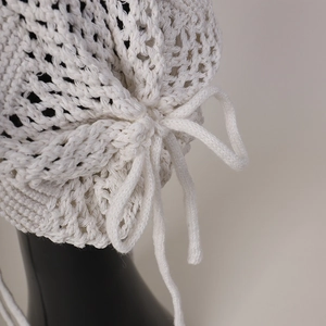 Détail du bonnet au crochet blanc avec tissage ajouré complexe et cordons de serrage