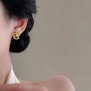 Gold plated rocking horse stud earrings with white zircon on model for a luxury look