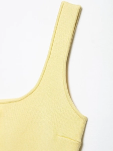 Detailed close-up of yellow knit top shoulder straps and neckline texture on white background