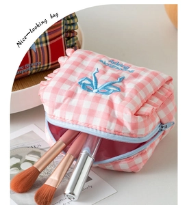 Detail of pink gingham makeup bag with blue bow embroidery and zipper closure
