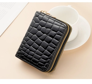 Detailed view of a black crocodile-patterned card holder on a minimalist desk